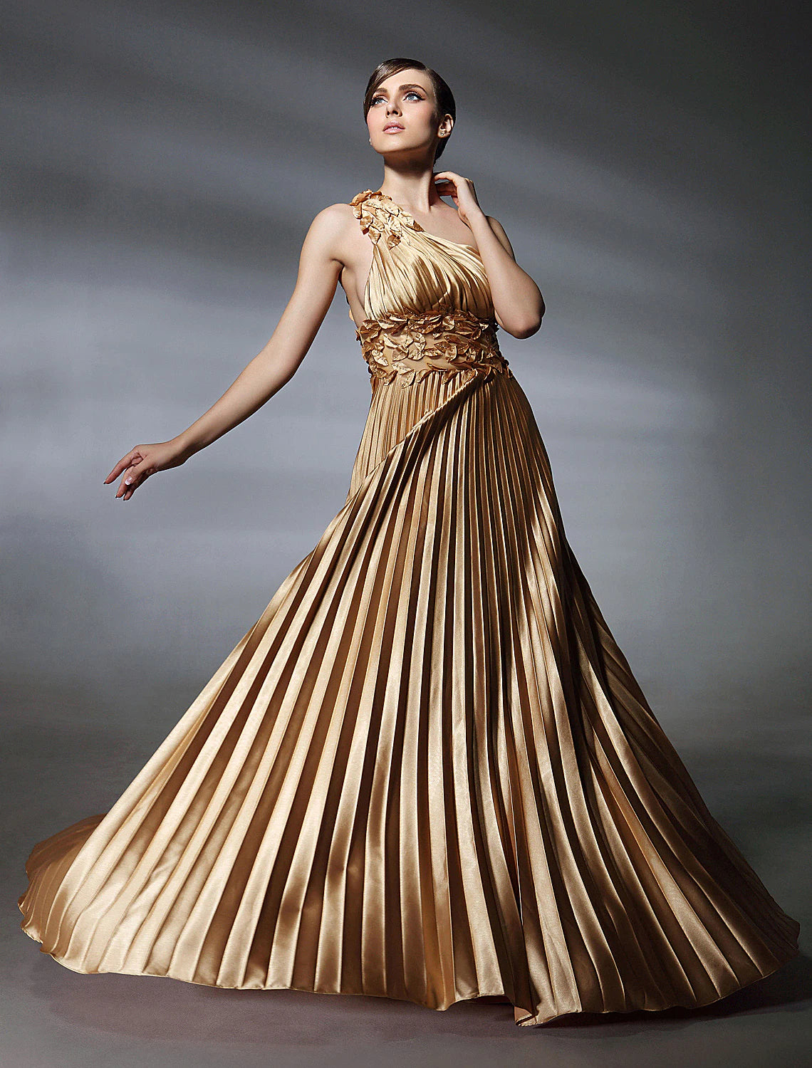 Elegant one-shoulder ball gown in stretch satin with pleats and beading.