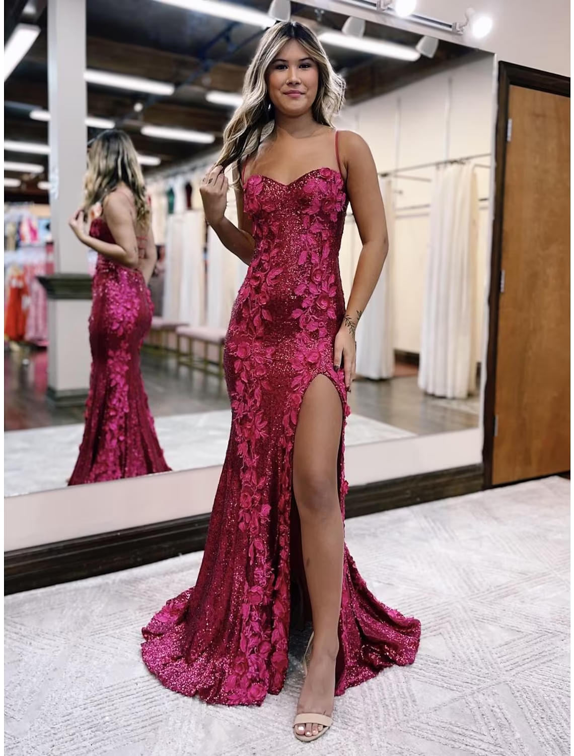 Full view of a woman wearing a sequined mermaid trumpet evening gown with spaghetti straps and a sweep train.