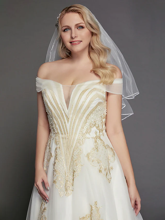 Close-up of the lace and illusion details on the off-shoulder wedding dress.