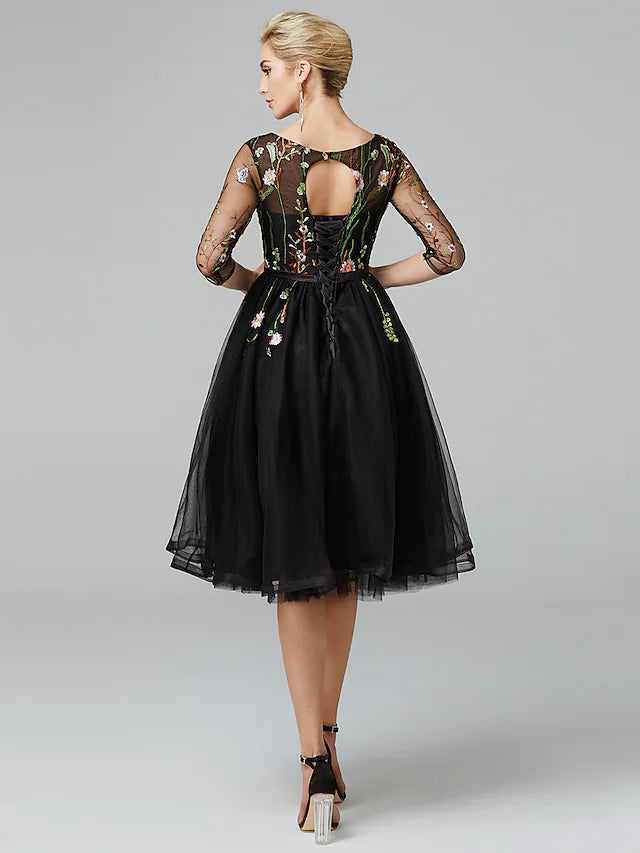Close-up detail of the intricate embroidery appliques on the tulle fabric of the black dress.