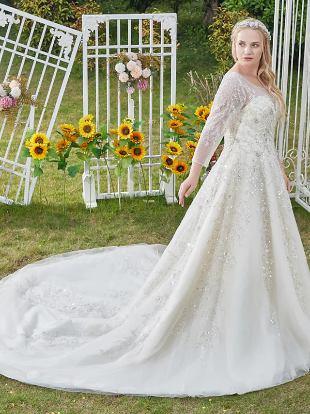 Model wearing a luxurious jewel neck ball gown wedding dress with 3/4 sleeves and lace details.