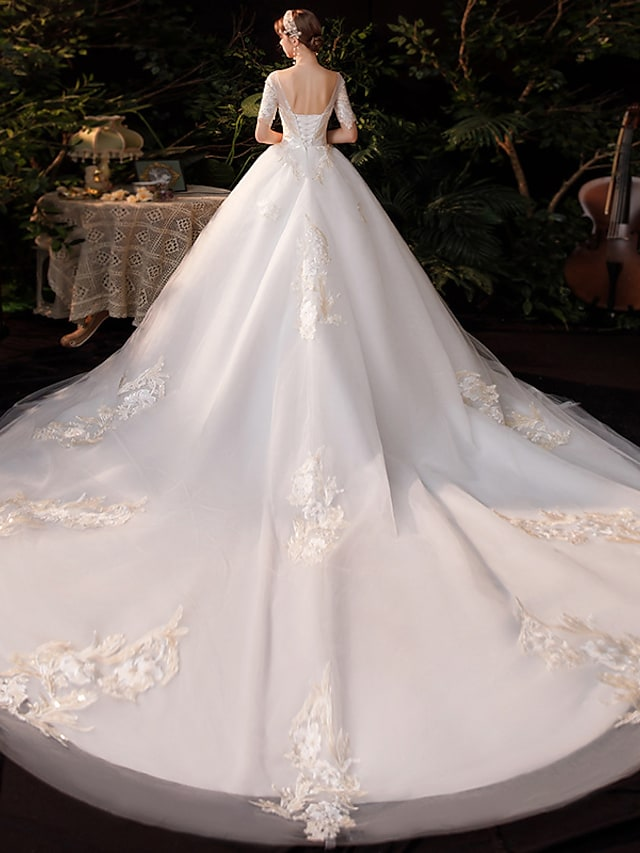 Back view of the princess ball gown wedding dress, showing the chapel train and intricate lace appliques.