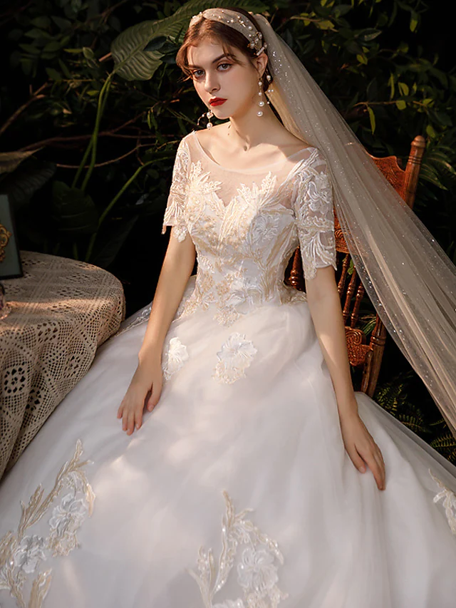 Close-up of the jewel neckline and short lace sleeves of the wedding dress.