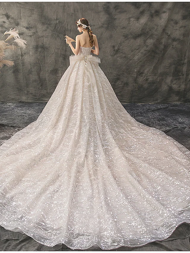 Side view of a bride wearing a strapless ball gown wedding dress.