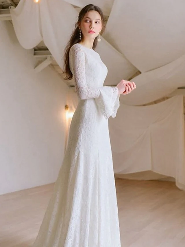 Bride posing in the romantic A-Line wedding dress with long lace sleeves.