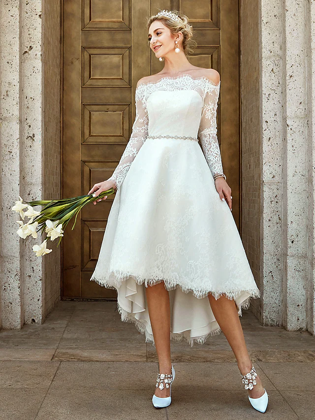 Close-up of the off-shoulder neckline and illusion lace sleeves on a wedding dress.