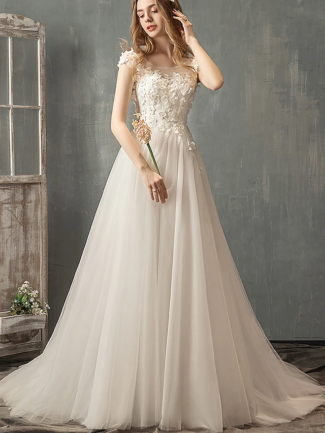 Front view of a romantic A-line wedding dress with jewel neck, lace, and tulle cap sleeves.