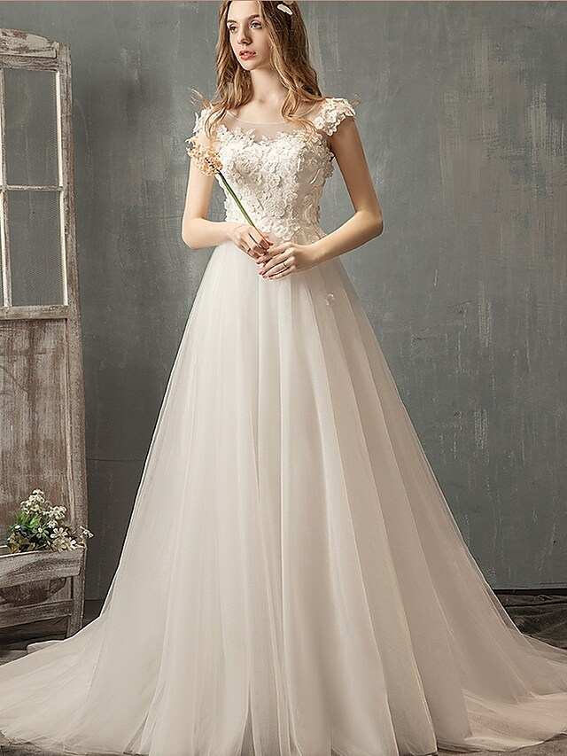 Close-up of the lace and applique details on the cap sleeve wedding dress.