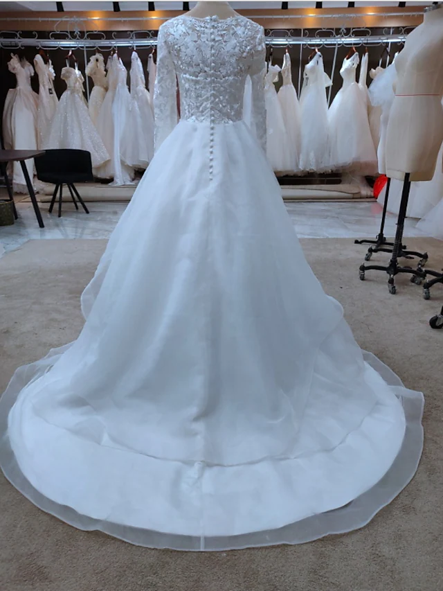 Side profile of the long sleeve A-line wedding gown with intricate lace details.