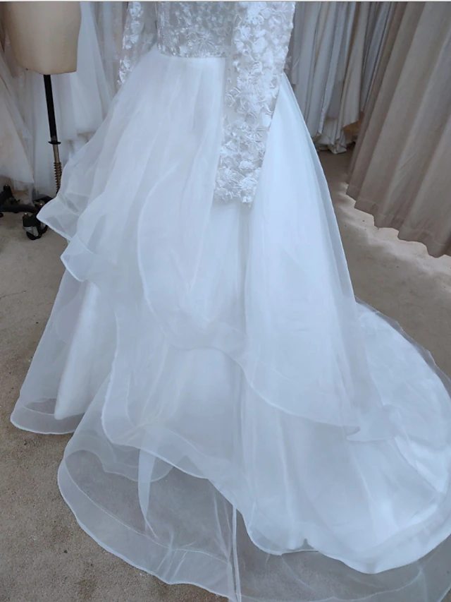 Detail of the lace and tulle fabric with delicate appliques on the bridal dress.