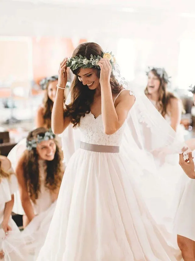 Front view of a romantic white spaghetti strap wedding dress with lace and tulle, featuring a court train.