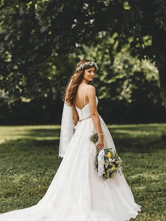 Back view of a white spaghetti strap wedding dress showcasing the court train and delicate appliques.