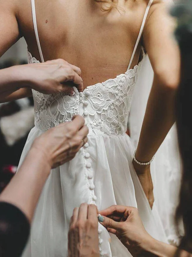Full length view of a white romantic wedding dress with spaghetti straps, lace, and tulle.