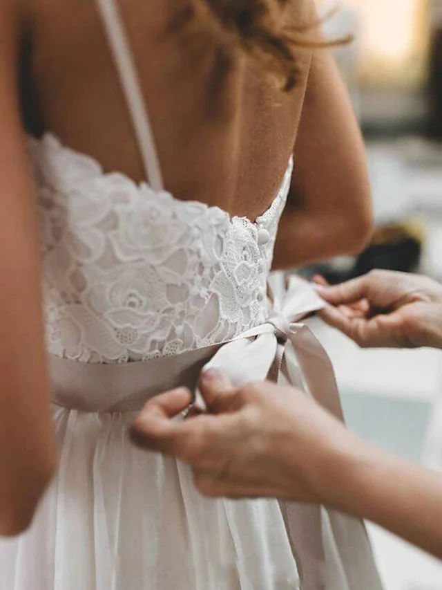 Detail of the sashes and pleats on a white wedding dress.