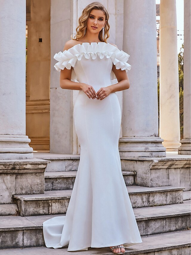 Full-length view of a woman posing in a white mermaid wedding dress.