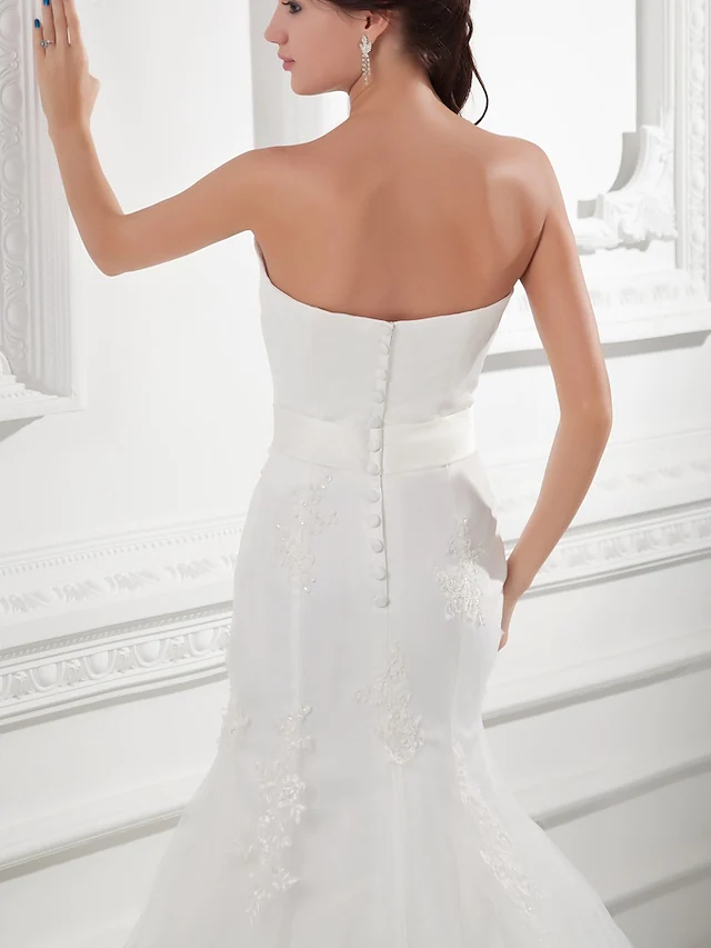 Back view of a strapless wedding gown showing button details and chapel train.