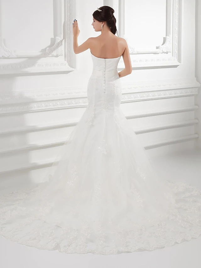 Side view of a bride wearing a strapless A-line wedding dress.