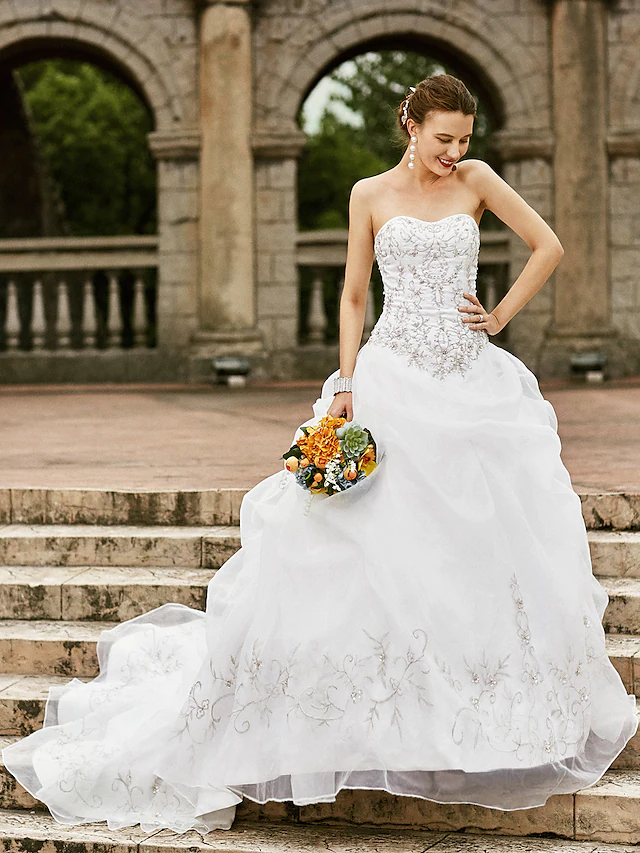 Front view of a romantic strapless ball gown wedding dress with intricate embroidery and a court train.