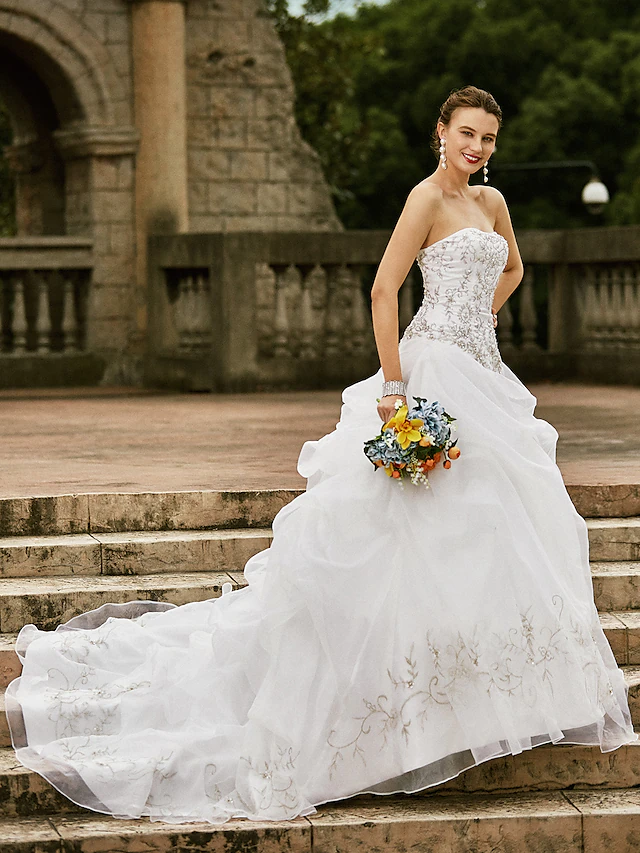 Close-up of the delicate floral embroidery on the bodice of a white wedding dress.