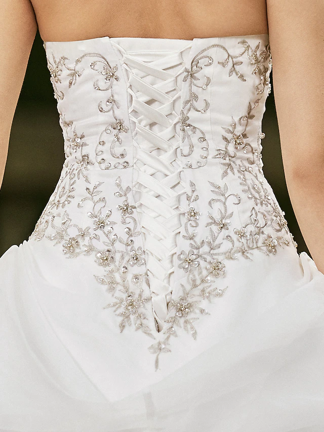 Bride gracefully posing in a strapless ball gown wedding dress with a flowing skirt.