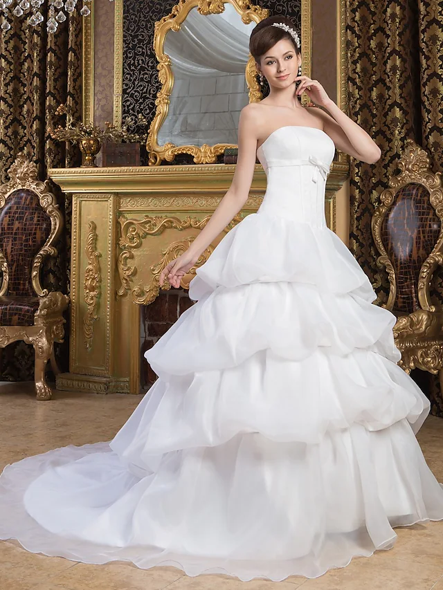 Strapless ball gown wedding dress with pick-up skirt and bow details.