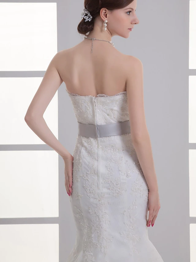 Elegant strapless wedding dress with sashes and ribbons detail.