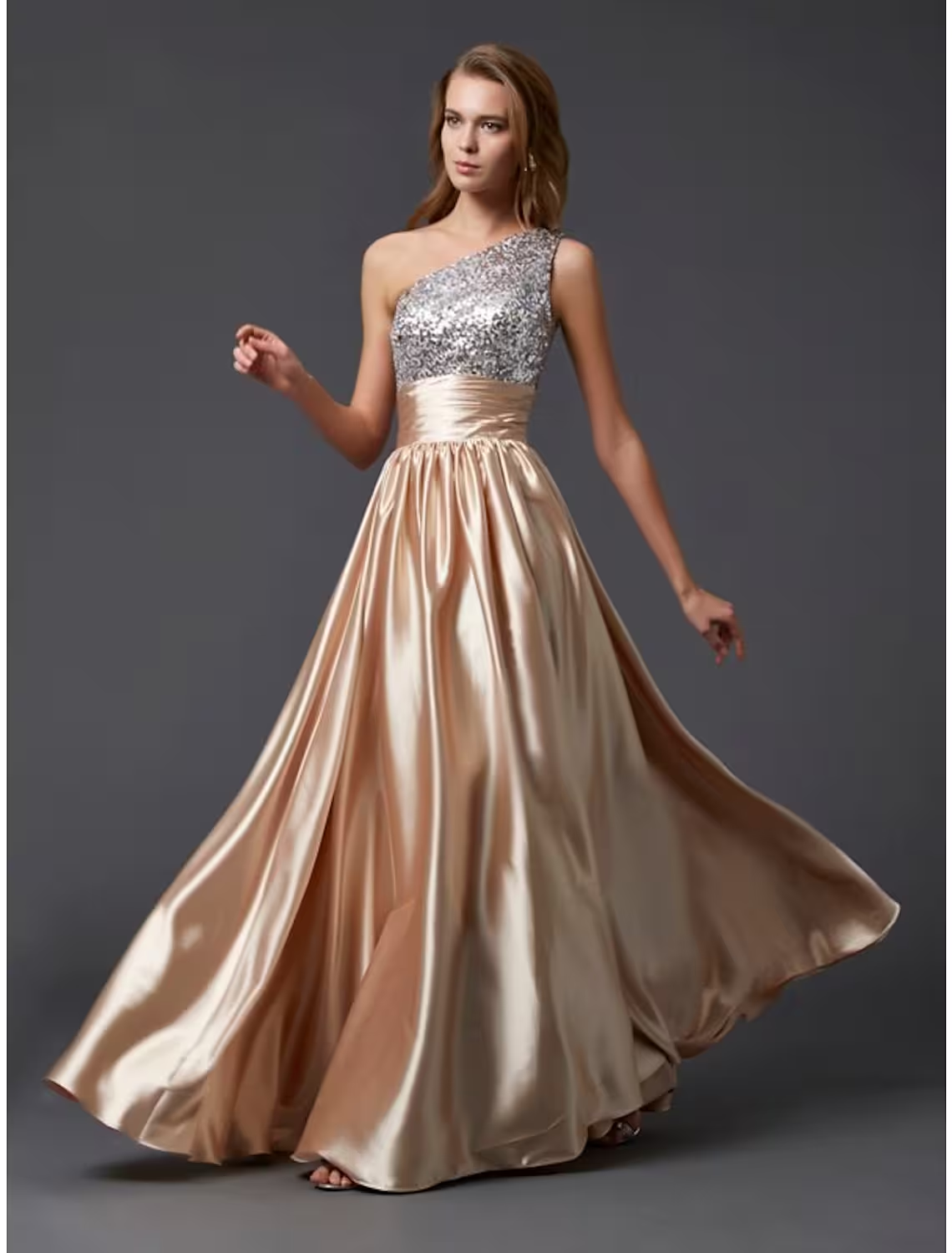 Woman wearing a shimmering silver A-line one-shoulder sequin prom dress with pleats.