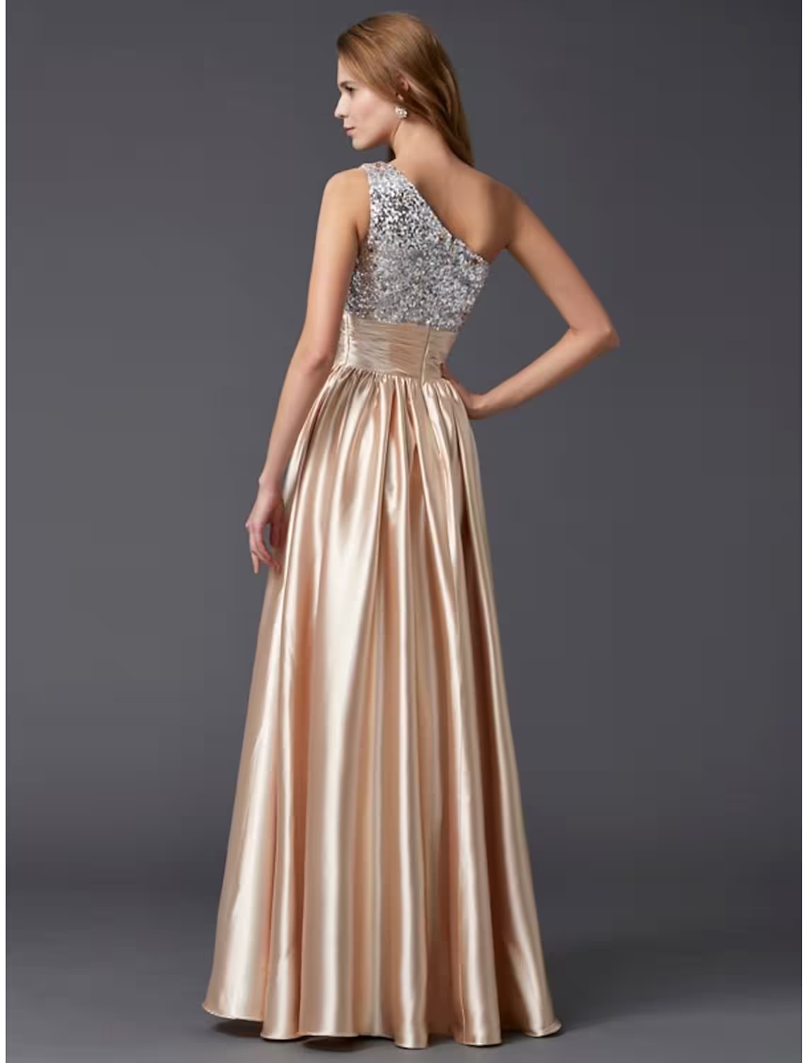 Back view of a woman in a floor-length A-line one-shoulder sequin prom dress.