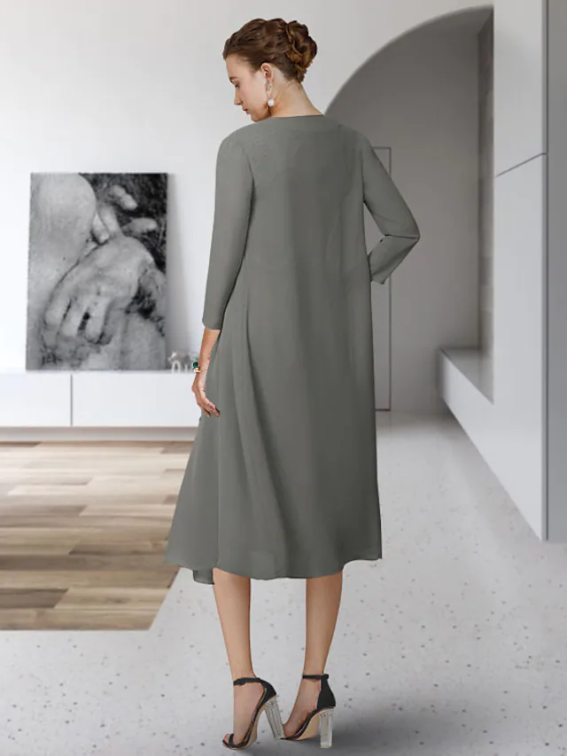 Woman posing in a sophisticated tea-length Mother of the Bride dress, highlighting the chiffon lace.