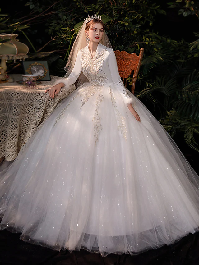 Romantic princess ball gown wedding dress with V-neck and long lace sleeves.