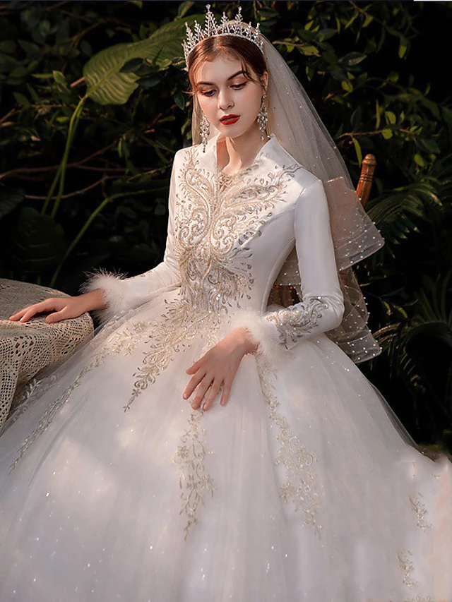 Close-up of the V-neckline and delicate long lace sleeves of the wedding dress.