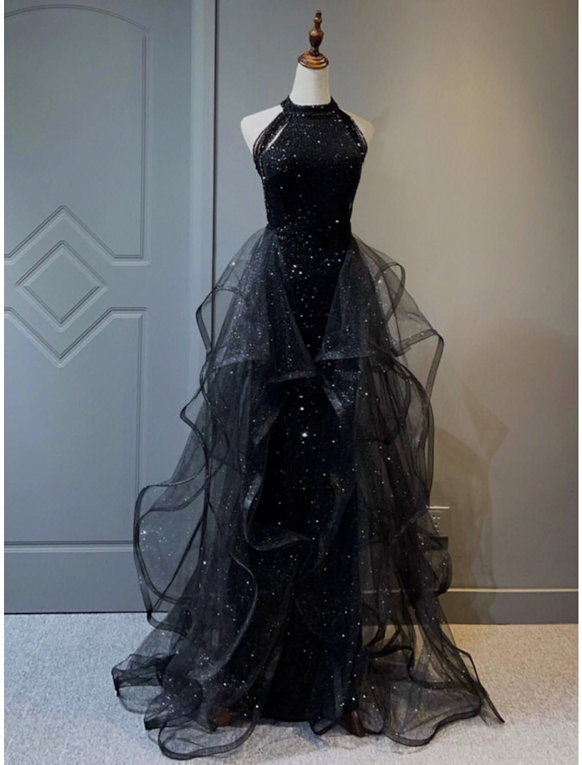 Full length view of a model wearing a sparkling A-Line halter prom dress.