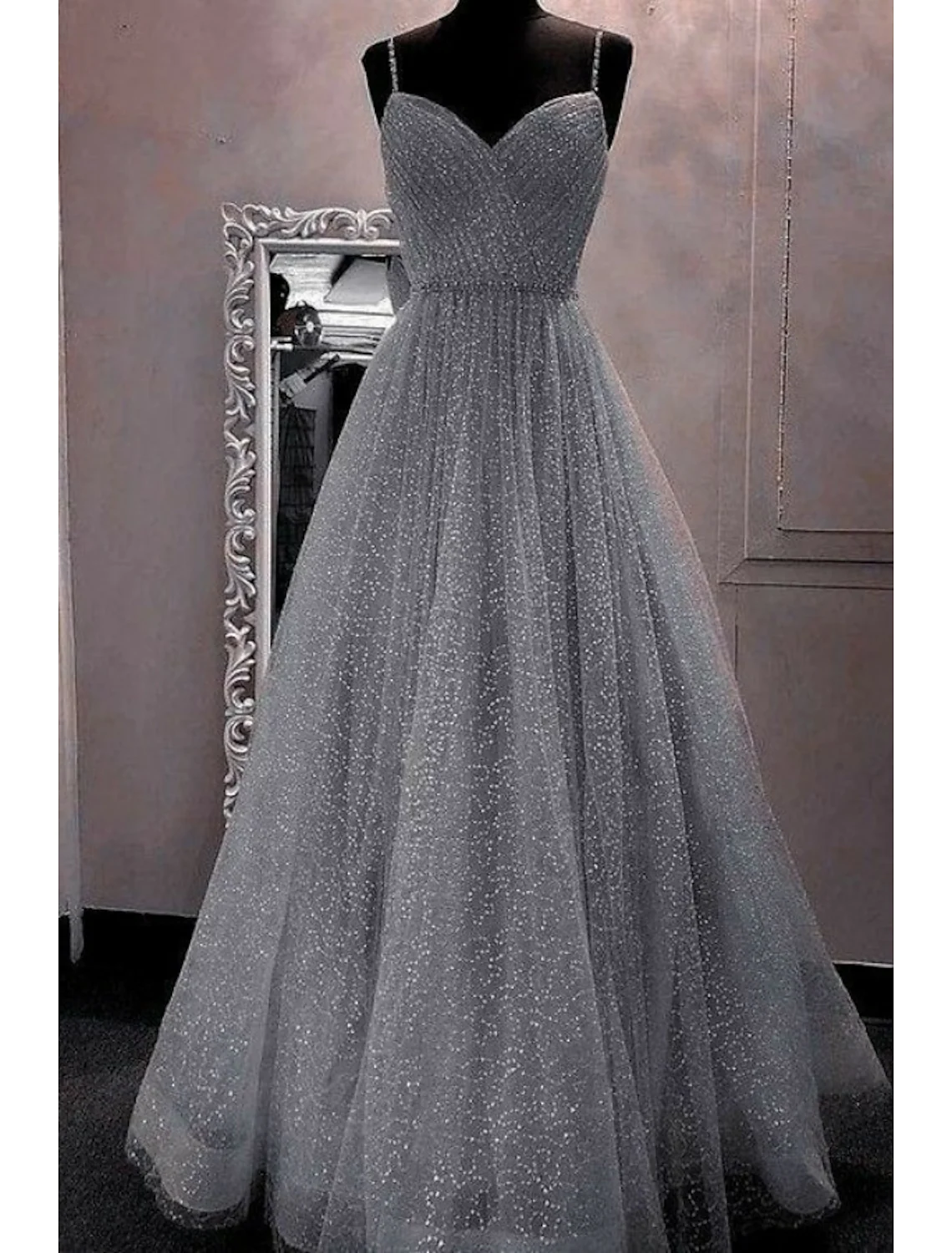 Woman in a sparkling pink A-line prom dress with spaghetti straps.