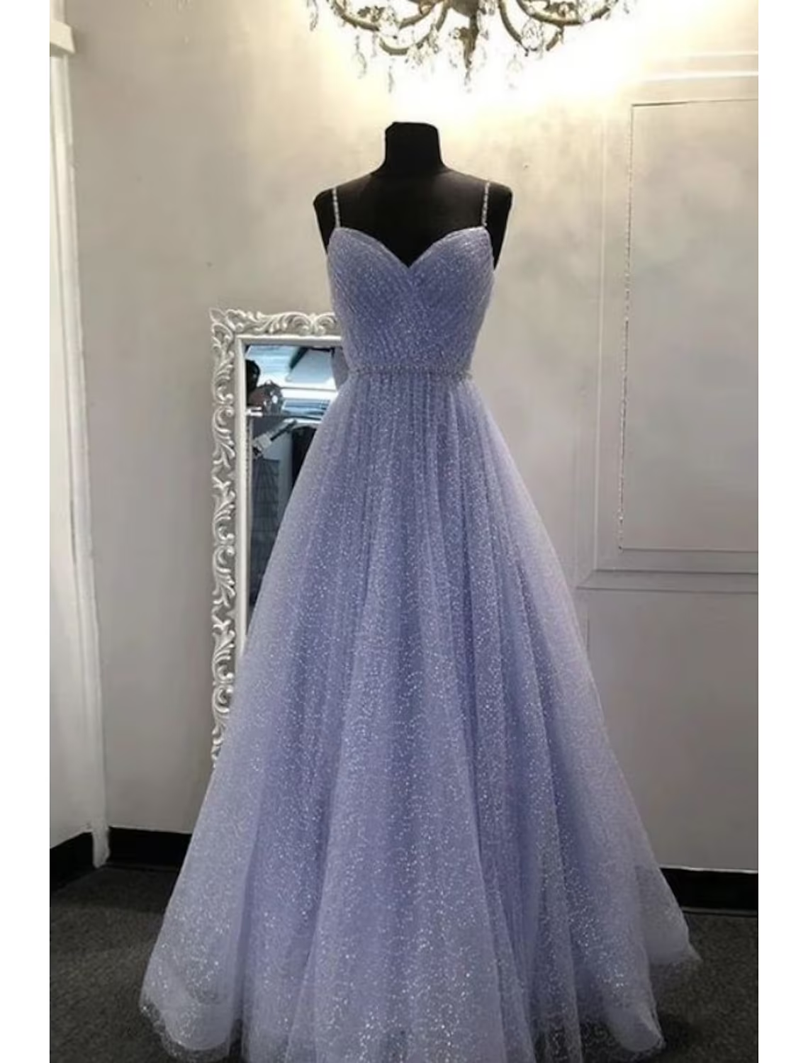 Woman in a sparkling green A-line prom dress with spaghetti straps.