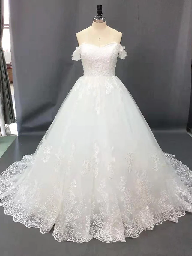 Back view of an elegant off shoulder wedding dress featuring a long court train.