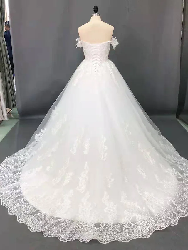 Close-up of lace appliques on a sparkling off shoulder bridal gown.