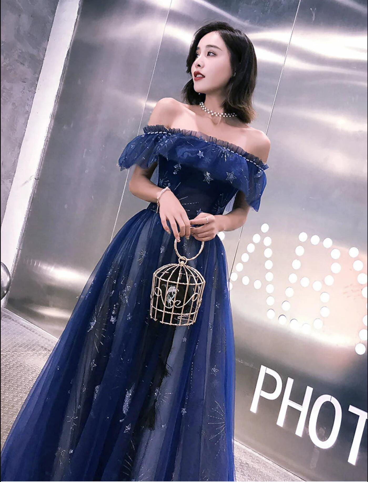 Model wearing a sparkling off-shoulder short sleeve tulle prom dress with sequins and embroidery.