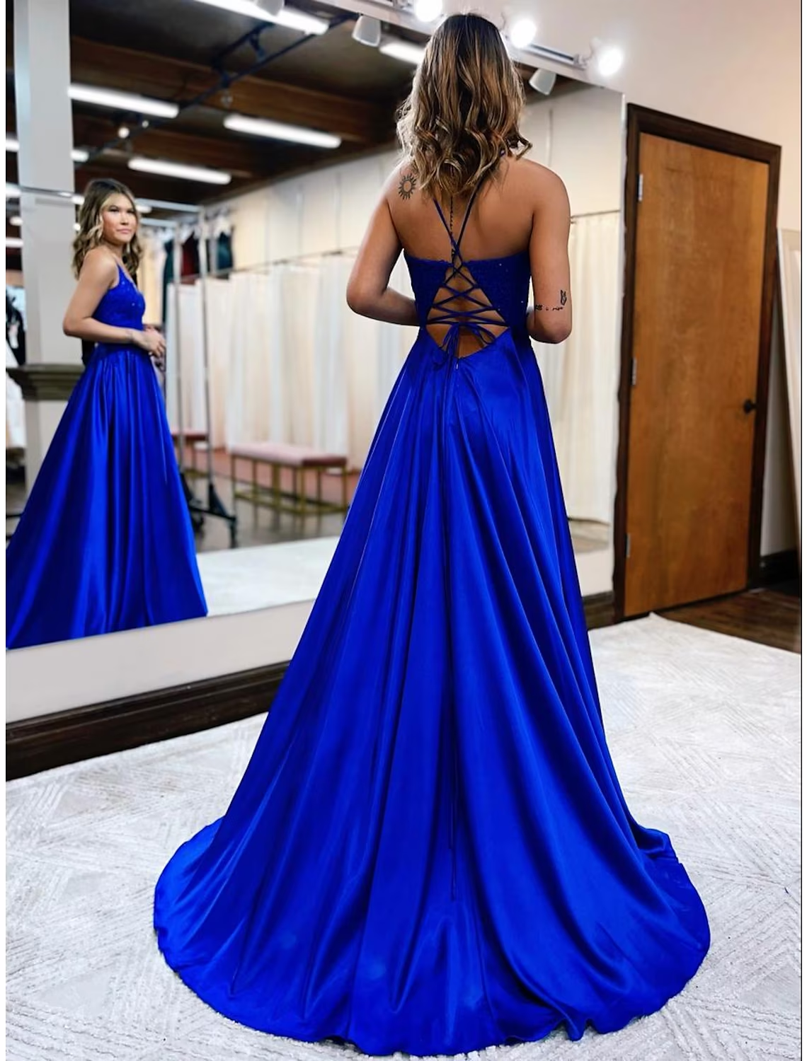 Back view of a light blue satin A-Line prom dress, featuring a backless design and flowing court train.