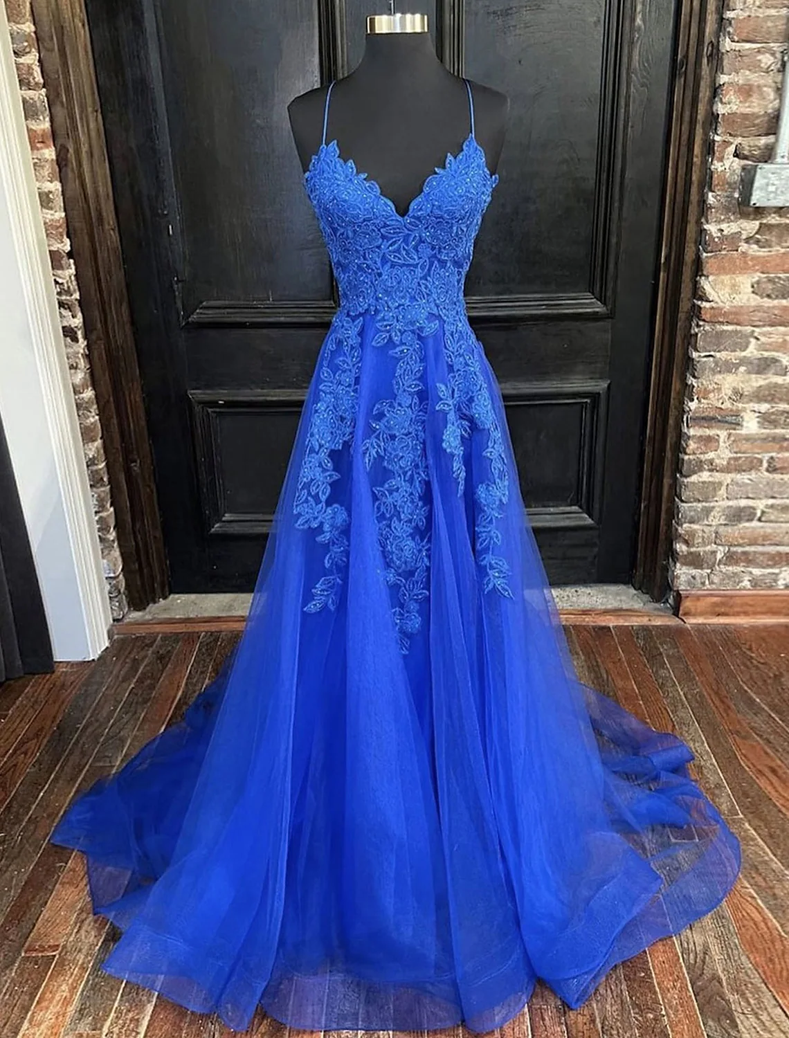 Model wearing an elegant A-line V-neck tulle prom dress with open back and intricate beading.