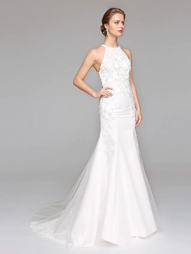Side profile of a bridal gown featuring a halter neck and lace tulle.