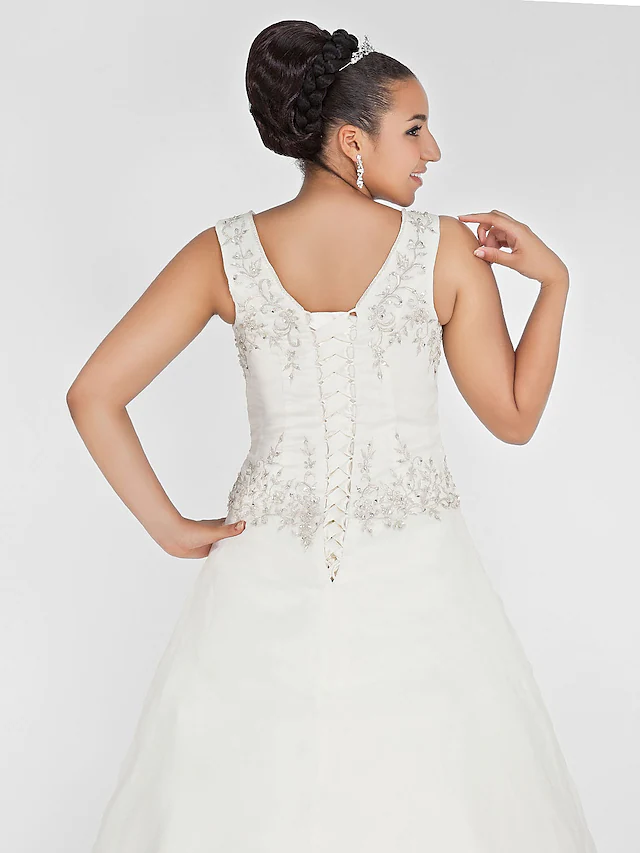 Bride posing in a V-neck lace wedding dress.