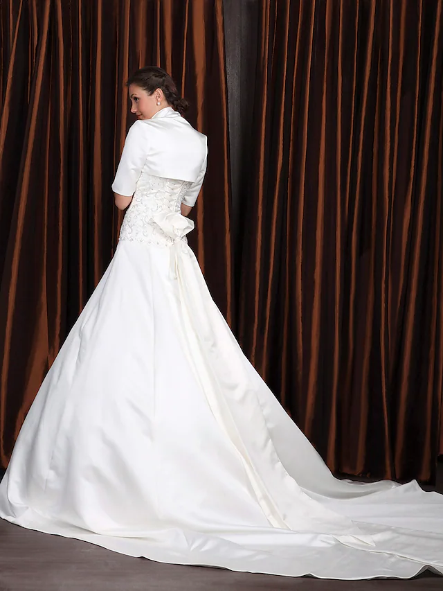 Side view of A-Line satin wedding dress, showing half sleeves and flowing cathedral train.